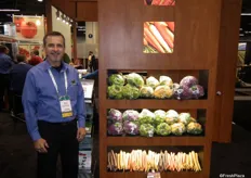 Douglas McFarland, Marketing Director of Colorful Harvest next to one of the company's showcases, showing heirloom carrots and cauliflowers.