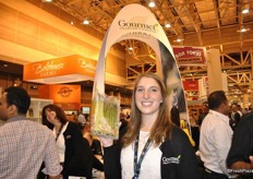 "Chloe Varennes of Gourmet Trading holds a tray of asparagus with a eco-friendly compostable biodegradable tray and recyclable film. Onthe back there is an explanation on how to cook asparagus. Gourmet also created a new booth with on the background: "L'arc de Gourmet"